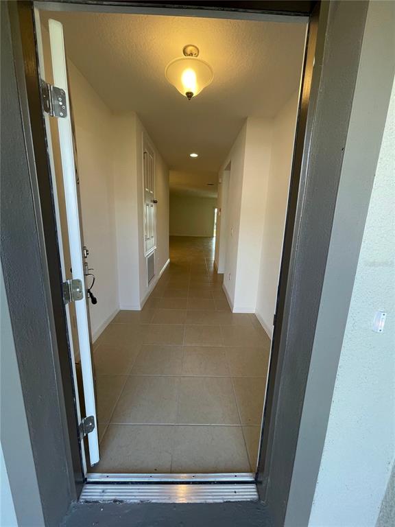 A view through an open doorway shows a tiled hallway with a ceiling light fixture — 5566 SABAL DRIVE, ST CLOUD, FL