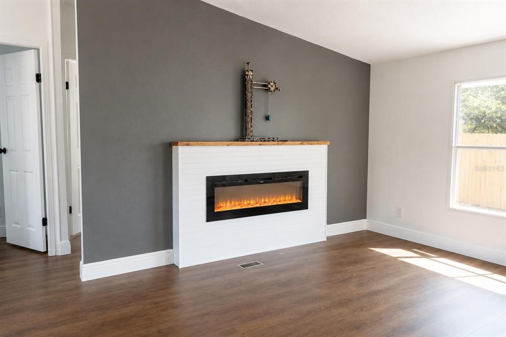A modern kitchen features white cabinets, a white island, dark countertops, and wood-look flooring — 1809 NE 162ND STREET, CITRA, FL