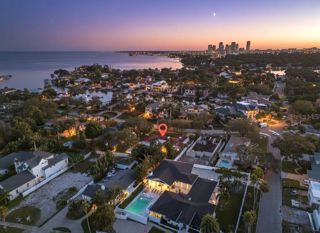 A backyard with a swimming pool, stone patio, and a single-story house at sunset — 1222 BRIGHTWATERS BOULEVARD NE, ST PETERSBURG, FL