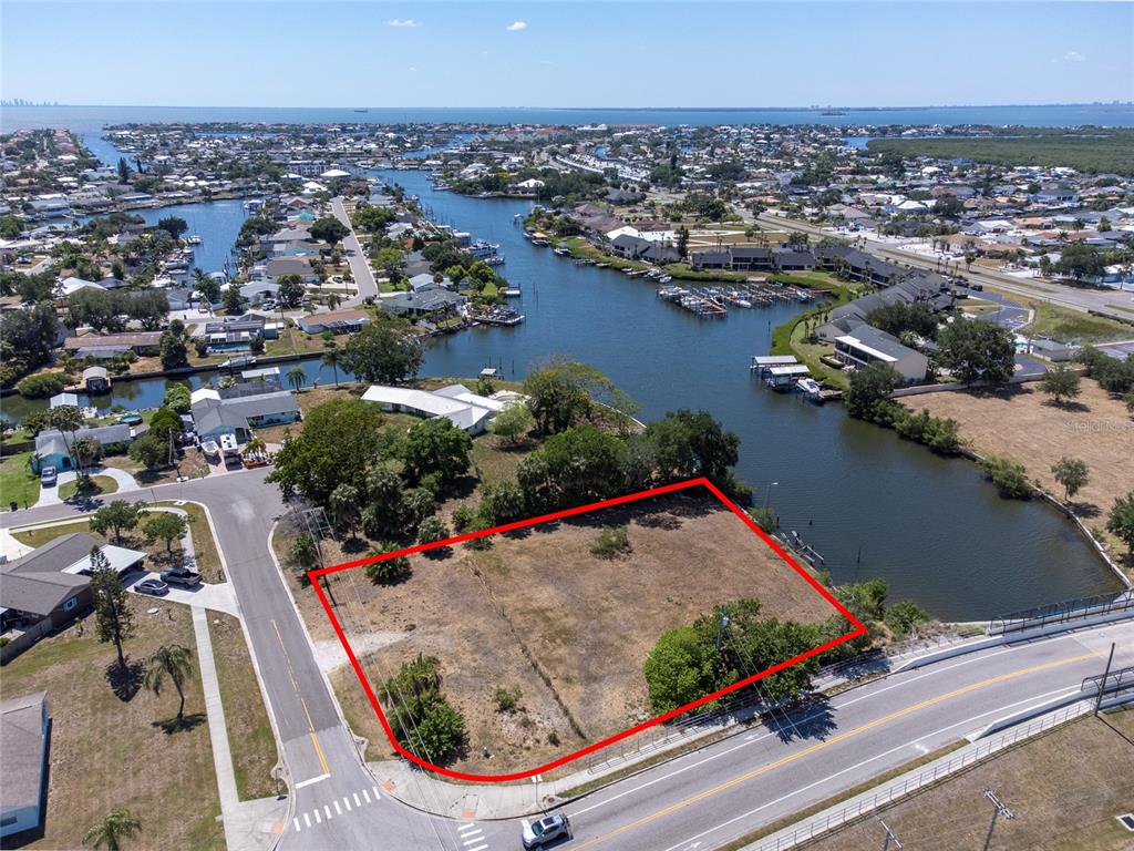 An aerial view shows a vacant, rectangular waterfront lot outlined in red next to a road — 601 FLAMINGO DRIVE, APOLLO BEACH, FL