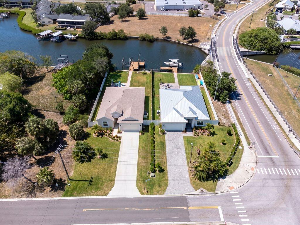 An aerial view shows two waterfront houses with private docks along a canal near a road — 601 FLAMINGO DRIVE, APOLLO BEACH, FL