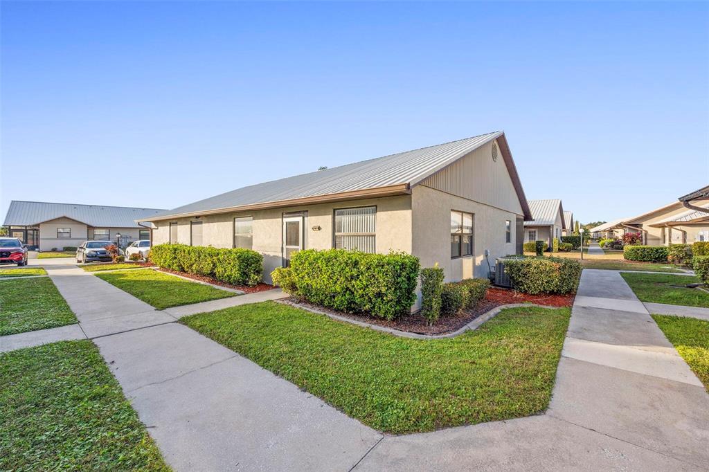 A single-story residential building with a metal roof and surrounding landscaping under a clear sky — 1916 VILLAWAY E, SEBRING, FL