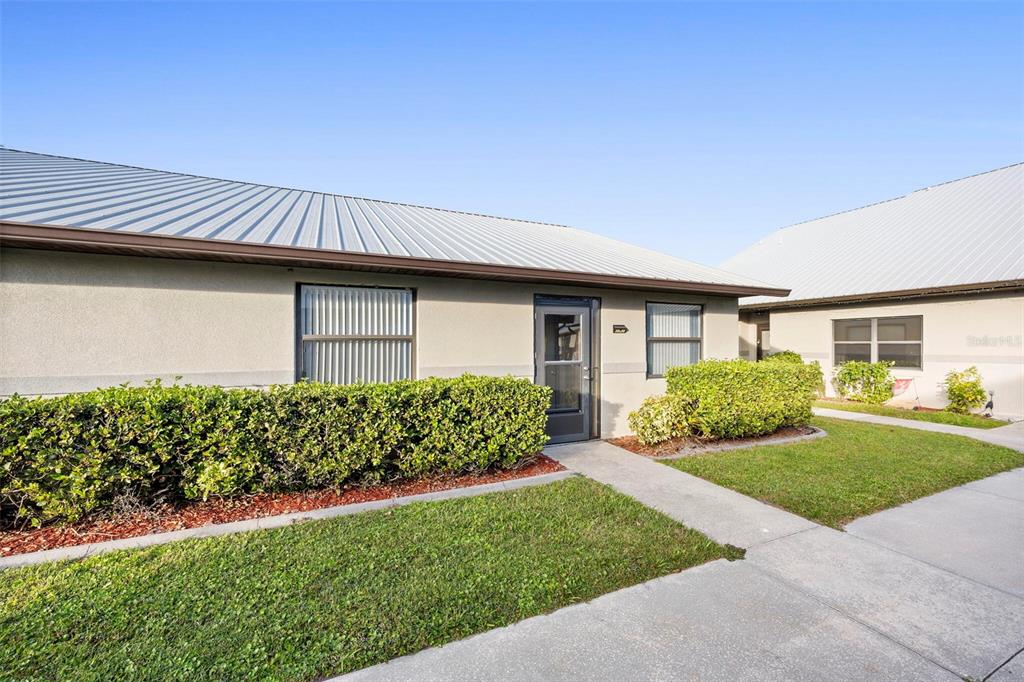 A single-story building with a metal roof, gray stucco walls, and a front hedge — 1916 VILLAWAY E, SEBRING, FL