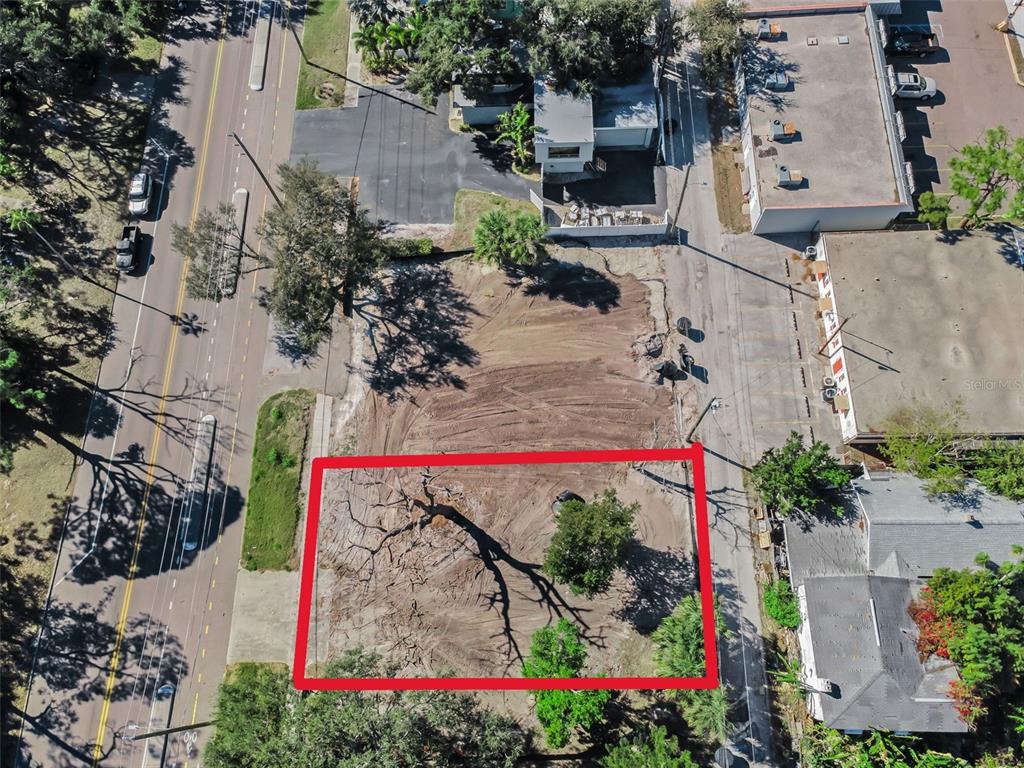 An aerial view shows a cleared, vacant lot situated between a road and commercial buildings — 7301 1ST AVENUE S, ST PETERSBURG, FL