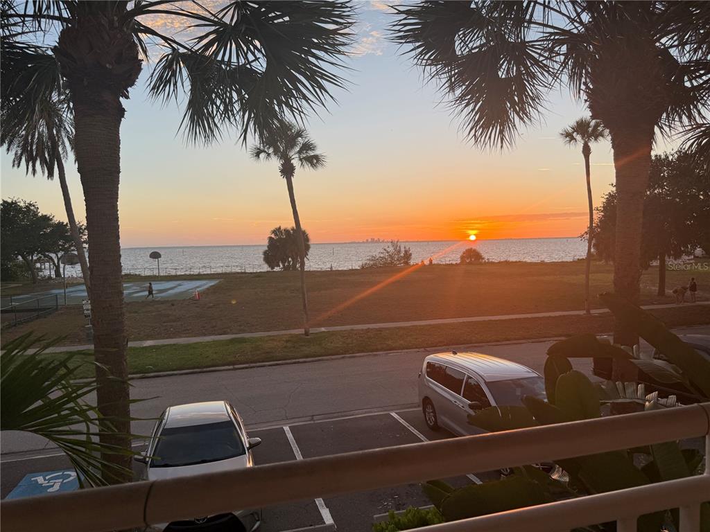 A view from a balcony overlooking a parking lot, a grassy park, and the ocean sunset — 611 DESTINY DRIVE UNIT 204, RUSKIN, FL