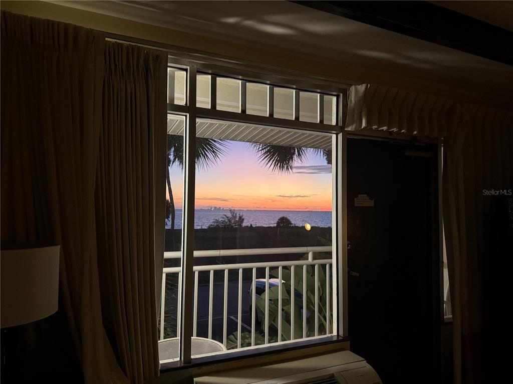 A view of a sunset over the ocean seen through a window in a room — 611 DESTINY DRIVE UNIT 204, RUSKIN, FL