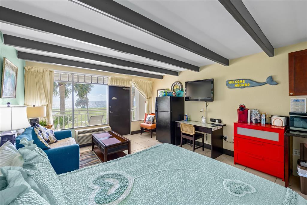 A bedroom with a view of the water, a red dresser, and exposed ceiling beams — 611 DESTINY DRIVE UNIT 204, RUSKIN, FL