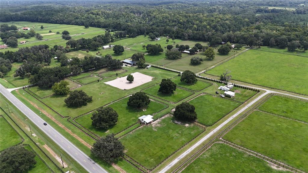An aerial view shows a large rural property with fenced pastures, trees, and outbuildings — 13489 NW GAINESVILLE ROAD, REDDICK, FL