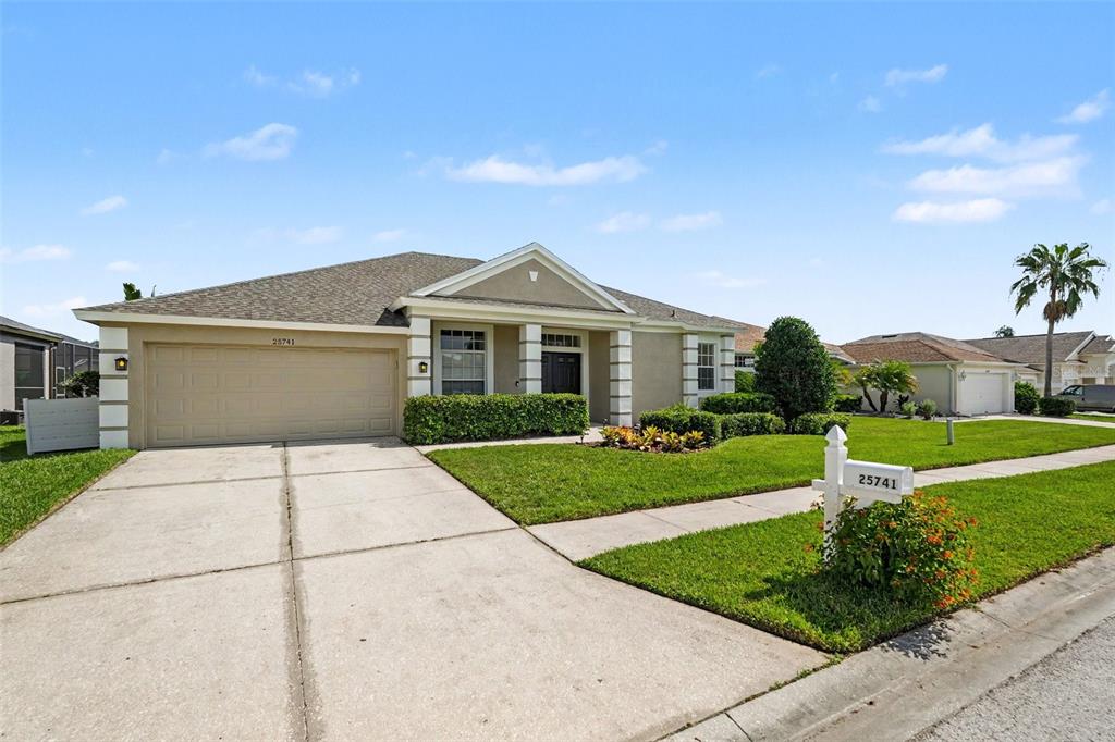 An aerial view shows suburban houses bordering a golf course with a pond — 25741 RISEN STAR DR, WESLEY CHAPEL, FL
