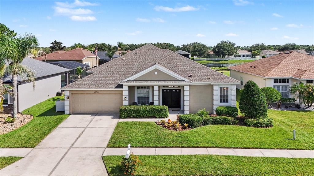 A kitchen with white cabinets and an island overlooks an open living and dining area — 25741 RISEN STAR DR, WESLEY CHAPEL, FL