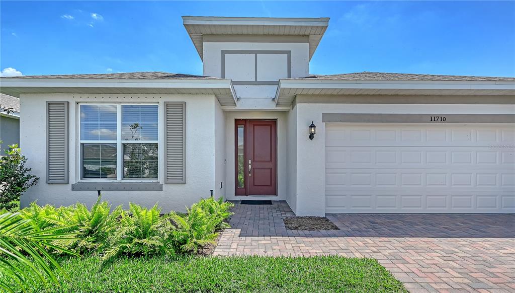 A single-story house exterior features a red front door, a garage, and a front lawn — 11710 LITTLE RIVER WAY, PARRISH, FL