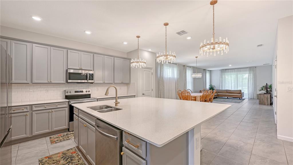 A kitchen with gray cabinets, a large white island, and an open-concept dining and living area — 11710 LITTLE RIVER WAY, PARRISH, FL