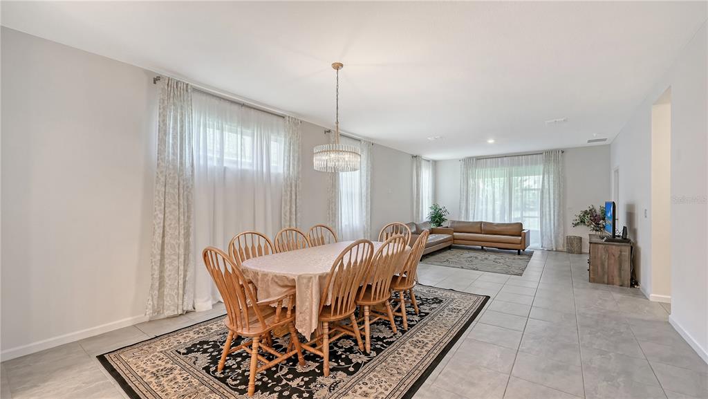 A dining area with a wooden table and chairs sits adjacent to a living room — 11710 LITTLE RIVER WAY, PARRISH, FL