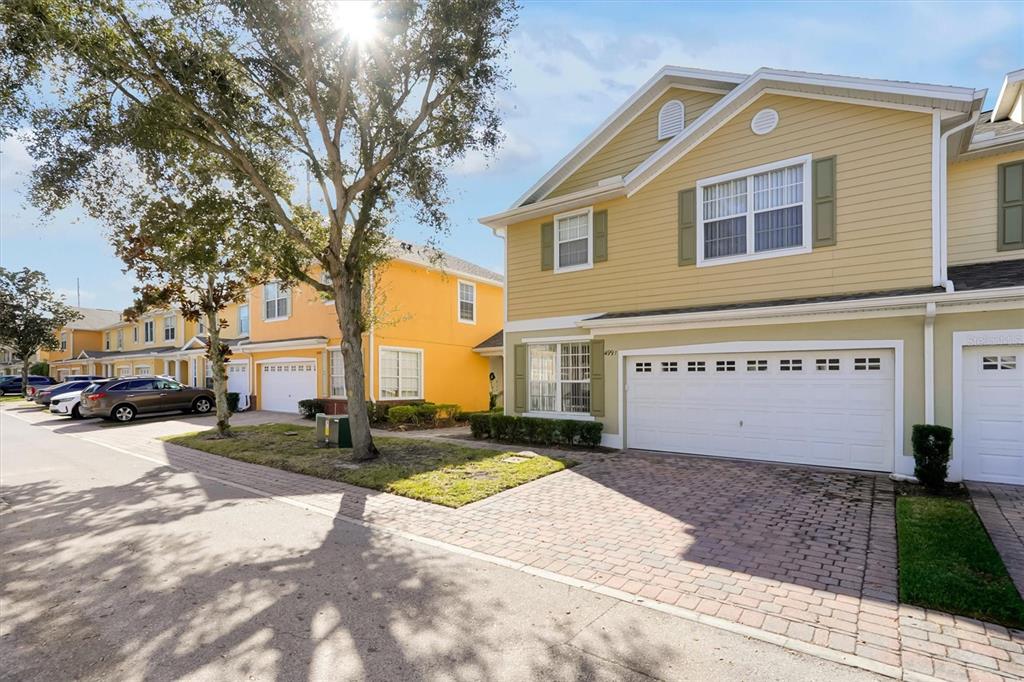 A street view of two-story townhomes with yellow and tan siding and paved driveways — 4991 ALITA TERRACE, ST CLOUD, FL