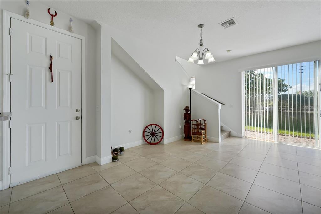 A tiled entryway features a white front door, a staircase, and a sliding glass door — 4991 ALITA TERRACE, ST CLOUD, FL