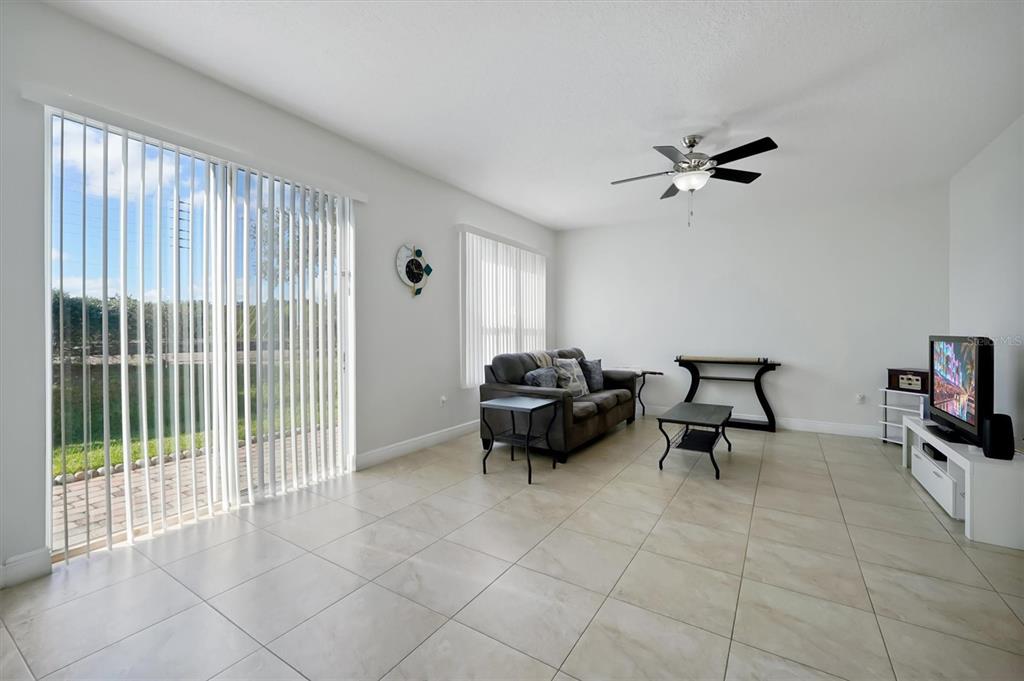 A living room with light tile floors, a sofa, a television, and sliding glass doors — 4991 ALITA TERRACE, ST CLOUD, FL