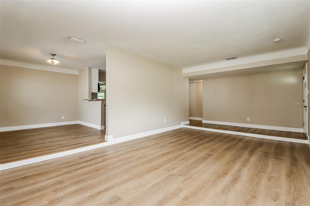 An open-concept living area features light wood-look flooring, beige walls, and a recessed dining space — 10293 SATSUMA ROAD, SEMINOLE, FL