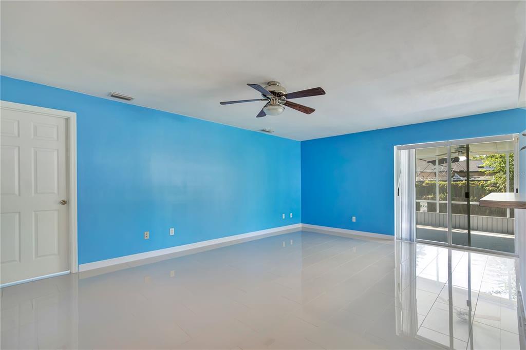 A bright blue room with white tile floors, a ceiling fan, and sliding glass doors — 561 15TH STREET, HOLLY HILL, FL