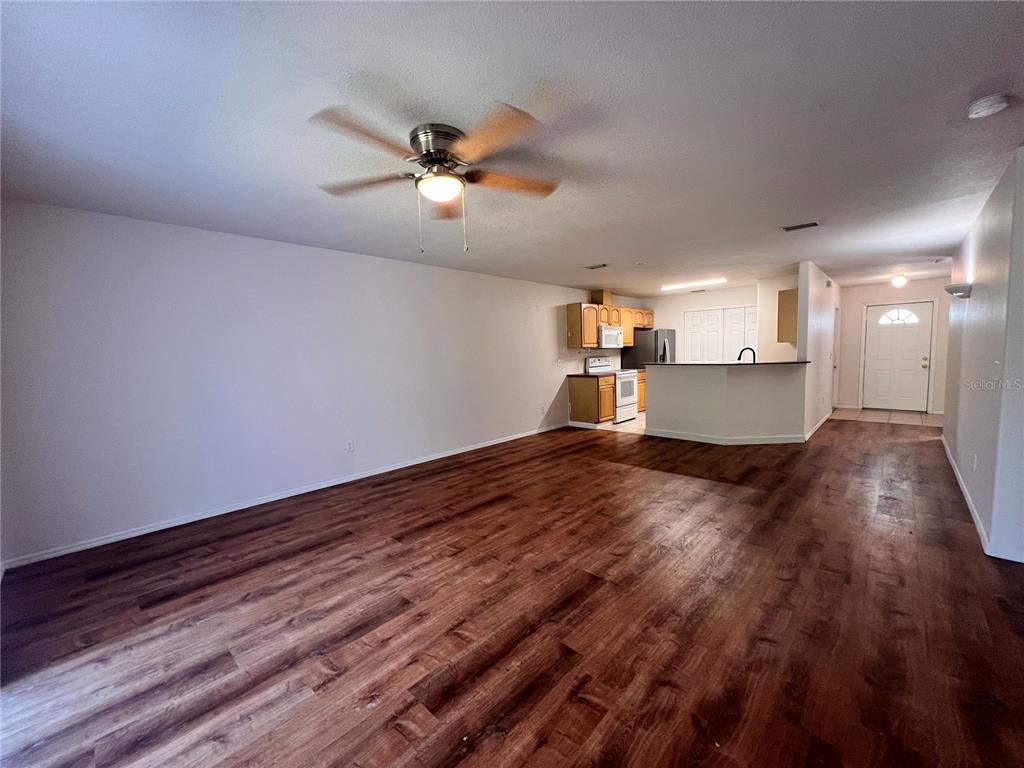 A living room with wood-look flooring leads to an open kitchen with a breakfast bar — 4 PROSPECT LANE UNIT A, PALM COAST, FL