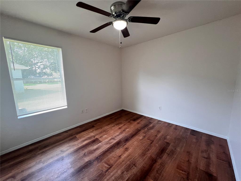 An empty room features wood-look flooring, a ceiling fan, and two sets of closet doors — 4 PROSPECT LANE UNIT A, PALM COAST, FL