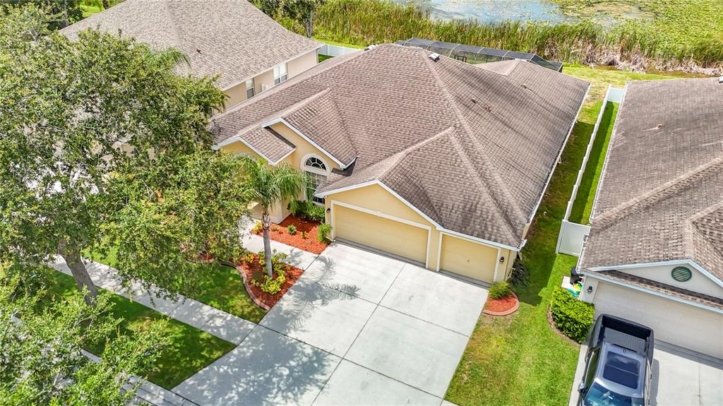 An aerial view shows a tan house with a brown roof, garage, and driveway — 8511 NORTHTON GROVES BOULEVARD, ODESSA, FL