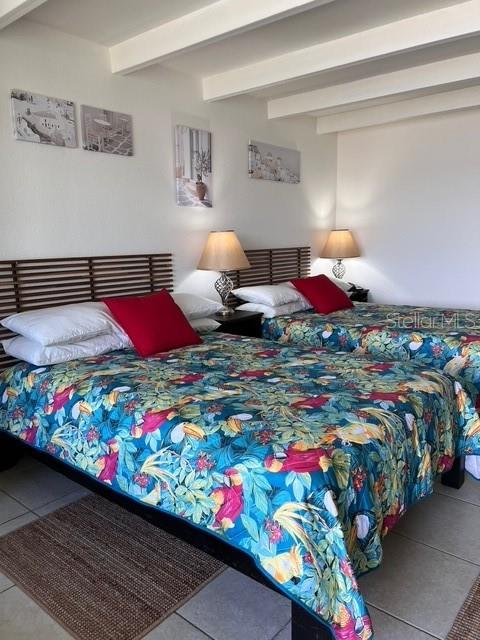 A bedroom features two beds with tropical-patterned bedding and red accent pillows — 611 DESTINY DRIVE UNIT 115, RUSKIN, FL