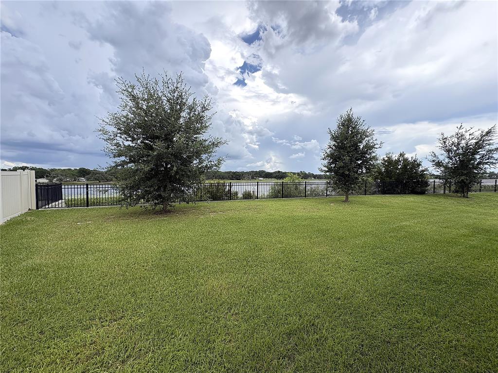 An open-concept kitchen and dining area features wood cabinets, granite countertops, and tile flooring — 1116 FOX PATH ROAD, DAVENPORT, FL