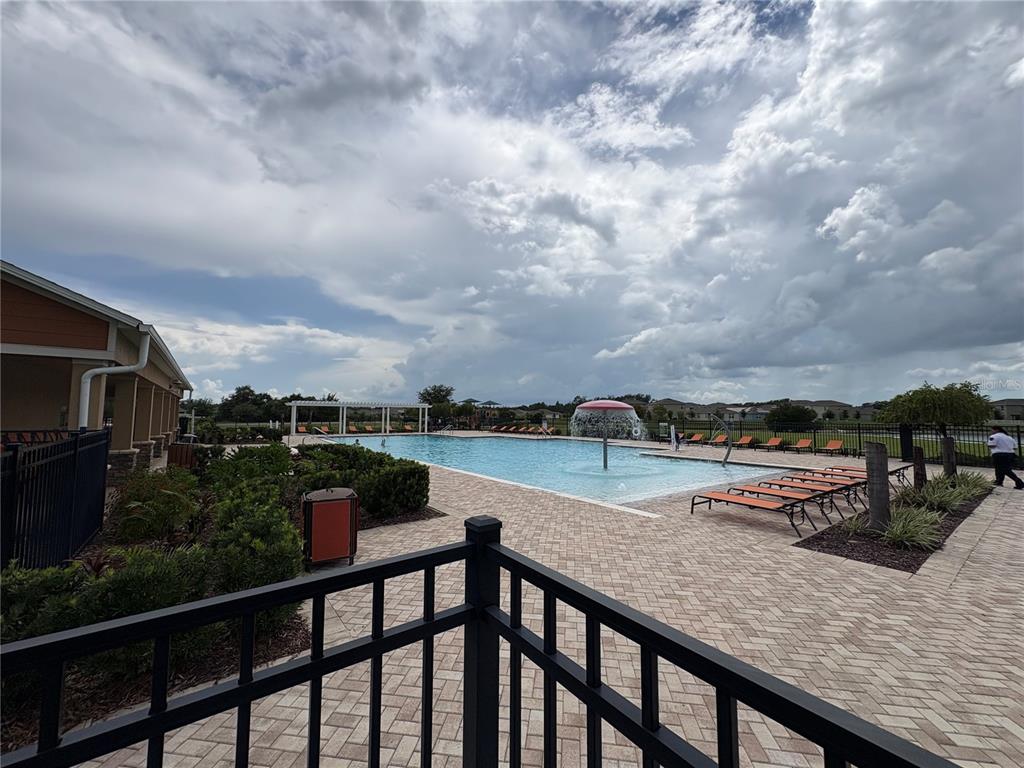 A kitchen features wood cabinets, granite countertops, a central island with seating, and stainless appliances — 1116 FOX PATH ROAD, DAVENPORT, FL