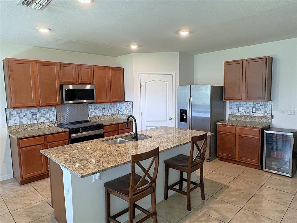 A living room features white leather furniture, a television, and tile flooring — 1116 FOX PATH ROAD, DAVENPORT, FL