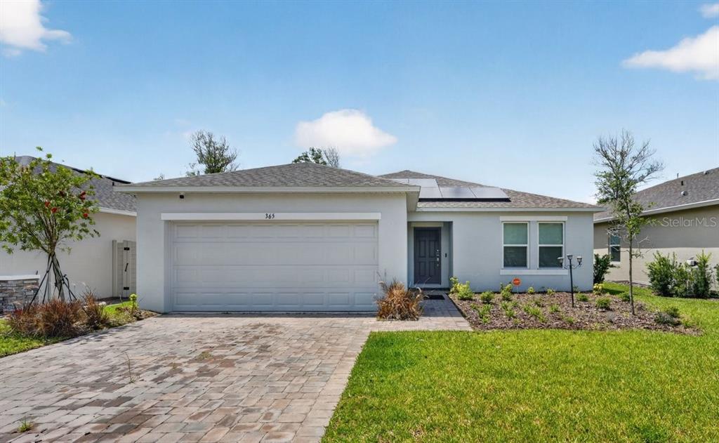 A single-story house with a paved driveway, a two-car garage, and solar panels on the roof — 365 RIVER FRONT WAY, EDGEWATER, FL