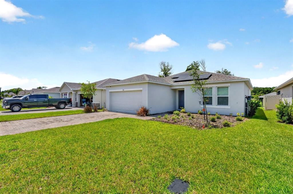 A single-story house with a two-car garage, solar panels, and a paved driveway — 365 RIVER FRONT WAY, EDGEWATER, FL