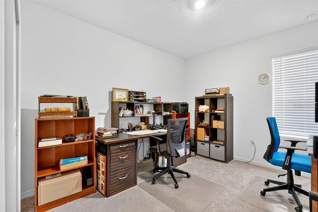 A home office with a desk, two chairs, and shelving units on carpeted flooring — 365 RIVER FRONT WAY, EDGEWATER, FL