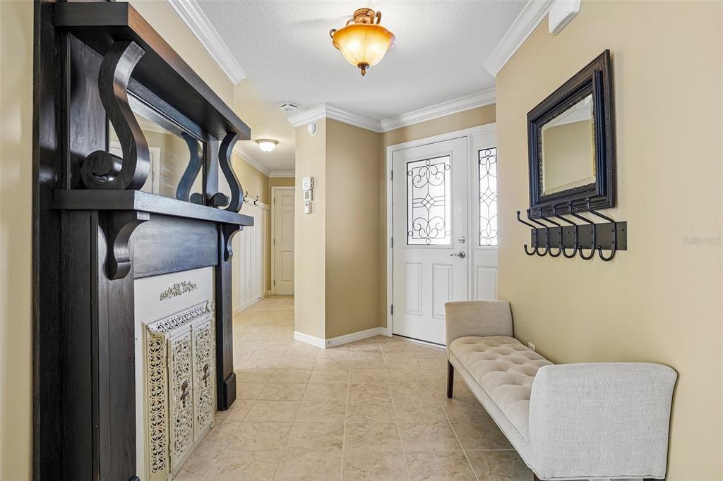 A foyer features a fireplace, a tufted bench, a coat rack, and a front door — 583 ARTEAGA WAY, THE VILLAGES, FL