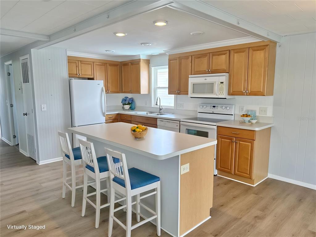 A kitchen features light wood cabinets, white appliances, a center island, and wood-look flooring — 6806 MOUNT QUINCY DRIVE NE UNIT 361, ST PETERSBURG, FL