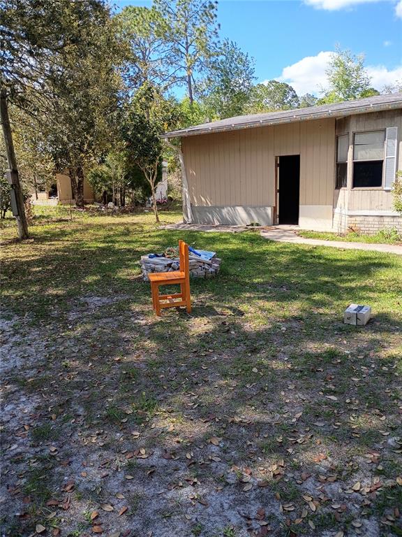 A wooden chair sits on a grassy lawn in front of a single-story house — 112 THOMPSON AVENUE, INTERLACHEN, FL