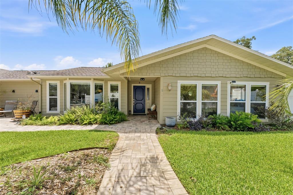 A light green house with a stone walkway leading to a dark blue front door — 6355 SEBRING STREET, WEEKI WACHEE, FL
