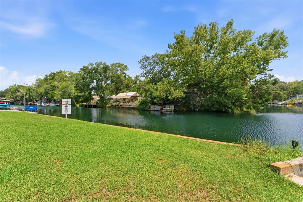 A grassy lawn overlooks a calm canal lined with trees and waterfront homes — 6355 SEBRING STREET, WEEKI WACHEE, FL
