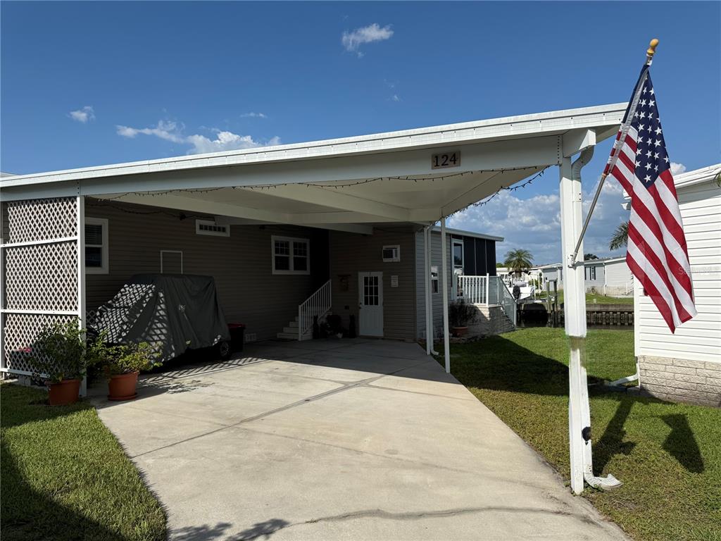 A manufactured home with a concrete driveway, a large carport, and a view of water — 124 AMERICANA COURT NE UNIT 214, ST PETERSBURG, FL