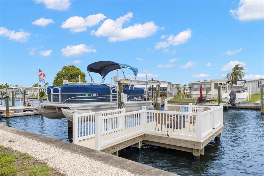 A mobile home with a screened-in porch, an attached carport, and a raised wooden deck — 124 AMERICANA COURT NE UNIT 214, ST PETERSBURG, FL