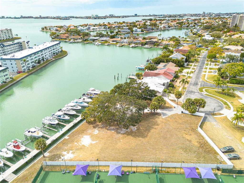 An aerial view shows a vacant waterfront lot with a boat dock and tennis courts — 5814 SKIMMER POINT BOULEVARD S, GULFPORT, FL