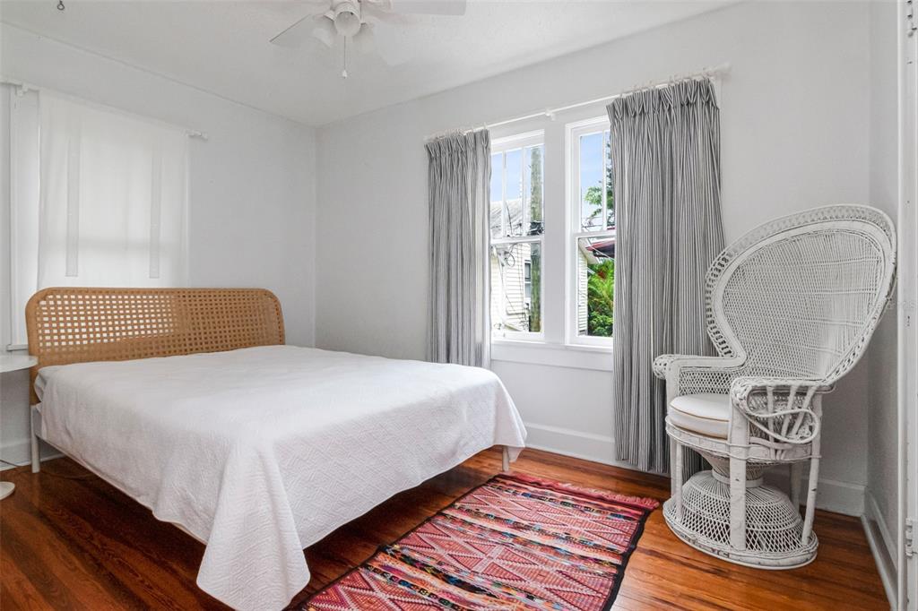A bedroom features a rattan headboard bed, a white wicker chair, and a patterned rug — 126 8TH AVENUE NE UNIT 1/2, ST PETERSBURG, FL