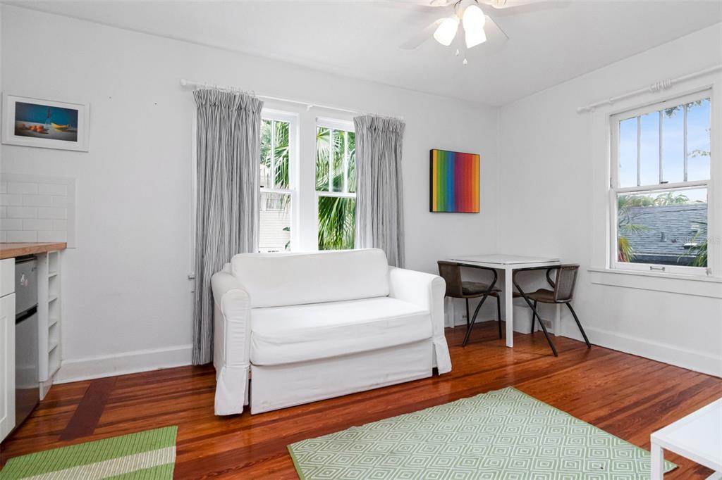 A bright room features a white sofa, a small dining table, and hardwood floors — 126 8TH AVENUE NE UNIT 1/2, ST PETERSBURG, FL