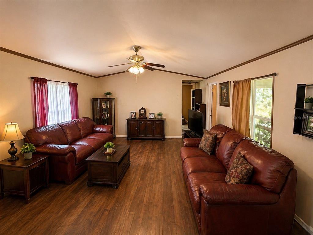 A living room features two brown leather sofas, a coffee table, and wood-look flooring — 14051 NE 45TH PLACE, WILLISTON, FL