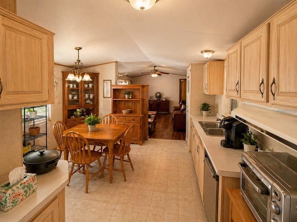 A kitchen with light wood cabinets and a dining area featuring a wooden table set — 14051 NE 45TH PLACE, WILLISTON, FL