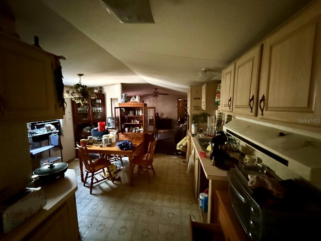 A kitchen and dining area with light wood cabinets, a wooden table, and vinyl flooring — 14051 NE 45TH PLACE, WILLISTON, FL