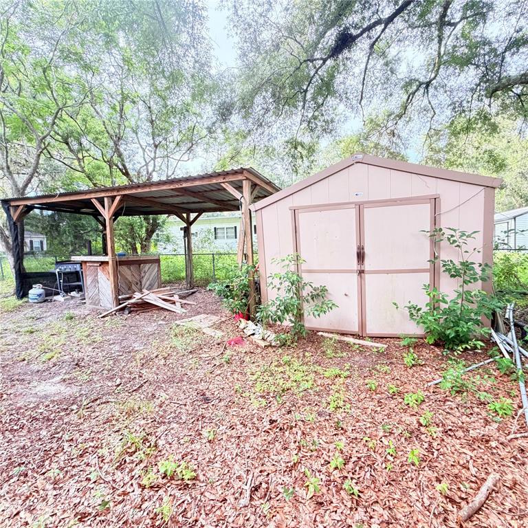 A backyard features a wooden storage shed next to a covered outdoor bar area — 20315 GREENWING ROAD, ALTOONA, FL