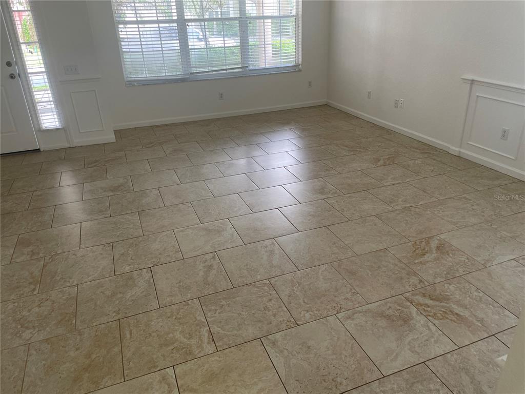 An empty room features beige tile flooring, white walls, and large windows with blinds — 8625 GREENBANK BLVD, WINDERMERE, FL