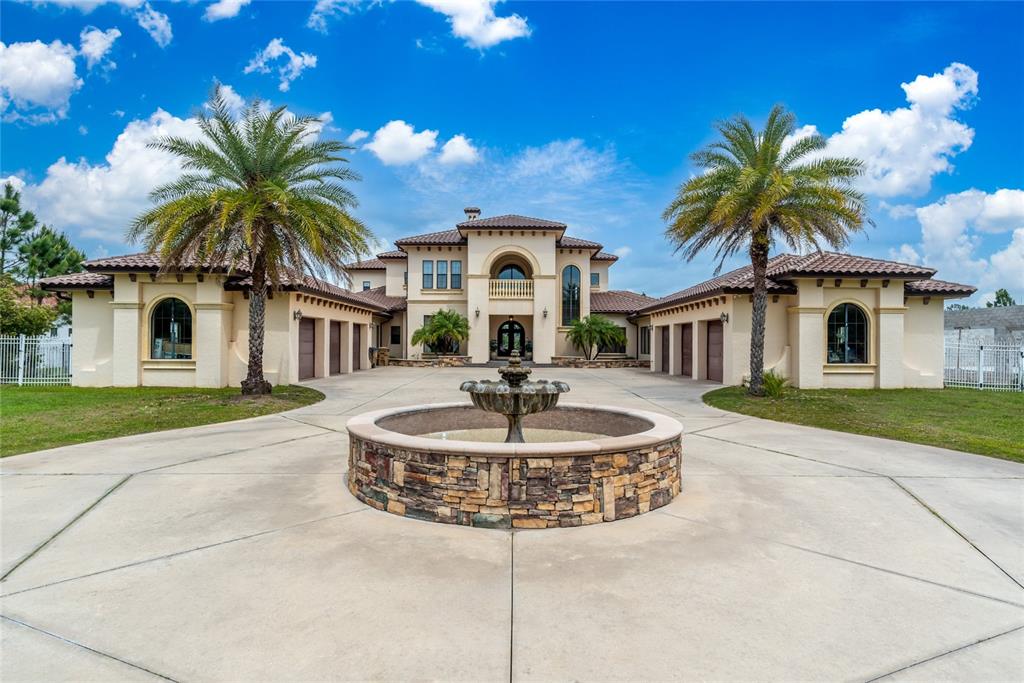 A large Mediterranean-style house features a circular stone fountain in a expansive concrete driveway — 5251 CARSON STREET, ST CLOUD, FL