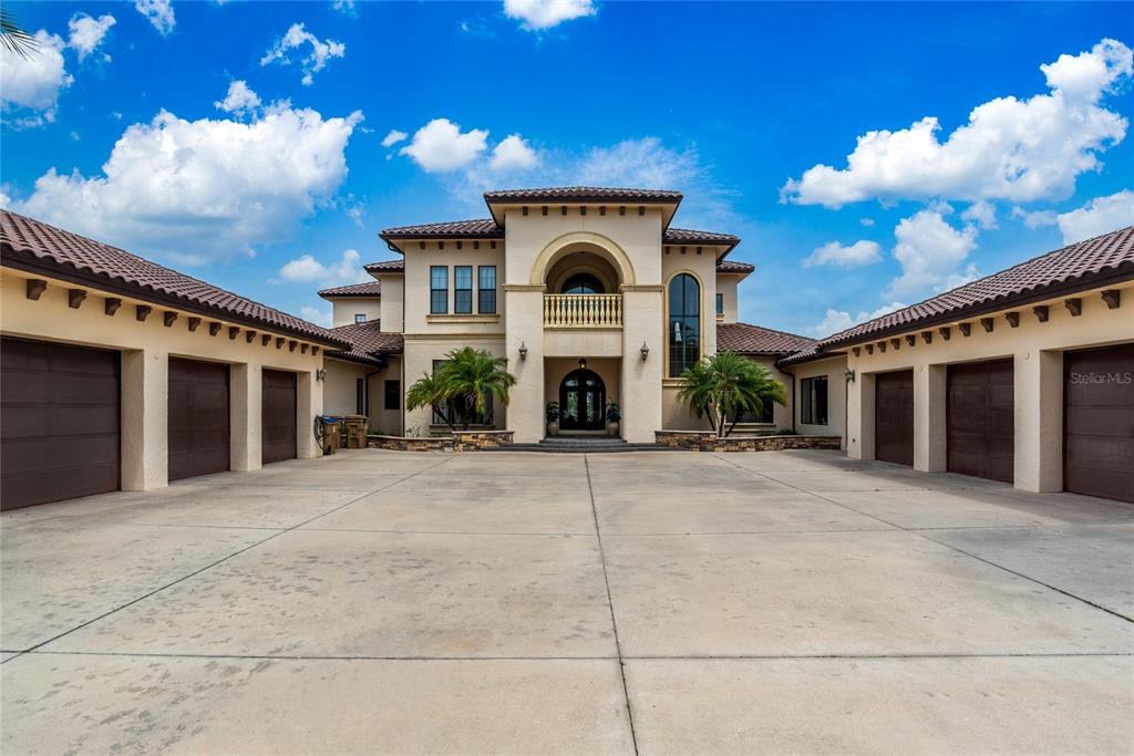 A large Mediterranean-style house features a central entrance, a balcony, and multiple garage bays — 5251 CARSON STREET, ST CLOUD, FL