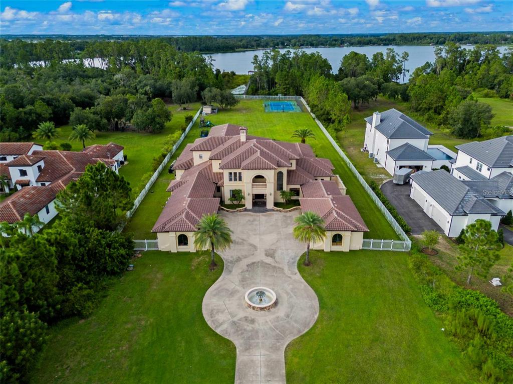 An aerial view of a large Mediterranean-style house with a circular driveway and tennis court — 5251 CARSON STREET, ST CLOUD, FL